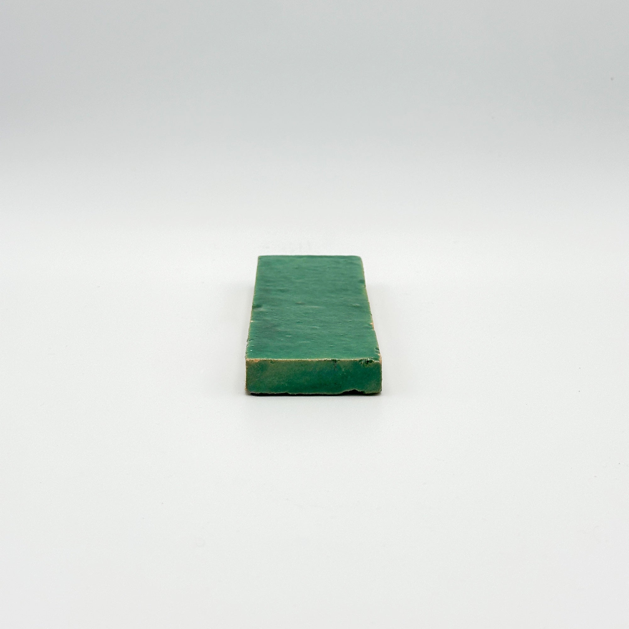 Bejmat émaillé vert émeraude, illustration du nuançage naturel et de la brillance d'un mur en terre cuite artisanale.